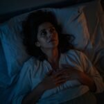 Como Parar de Pensar Demais, mulher brasileira deitada na cama à noite com olhos abertos e expressão de exaustão mental representando o overthinking e a dificuldade de parar de pensar demais antes de dormir