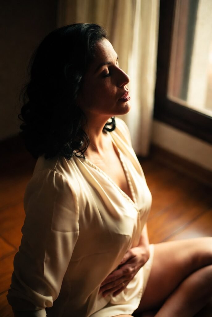 mulher brasileira sentada no chão com mãos no ventre e no peito praticando respiração controlada com olhos fechados e expressão de relaxamento progressivo representando a técnica de respiração 4-4-6 para ativar o sistema nervoso parassimpático e aliviar a ansiedade imediatamente