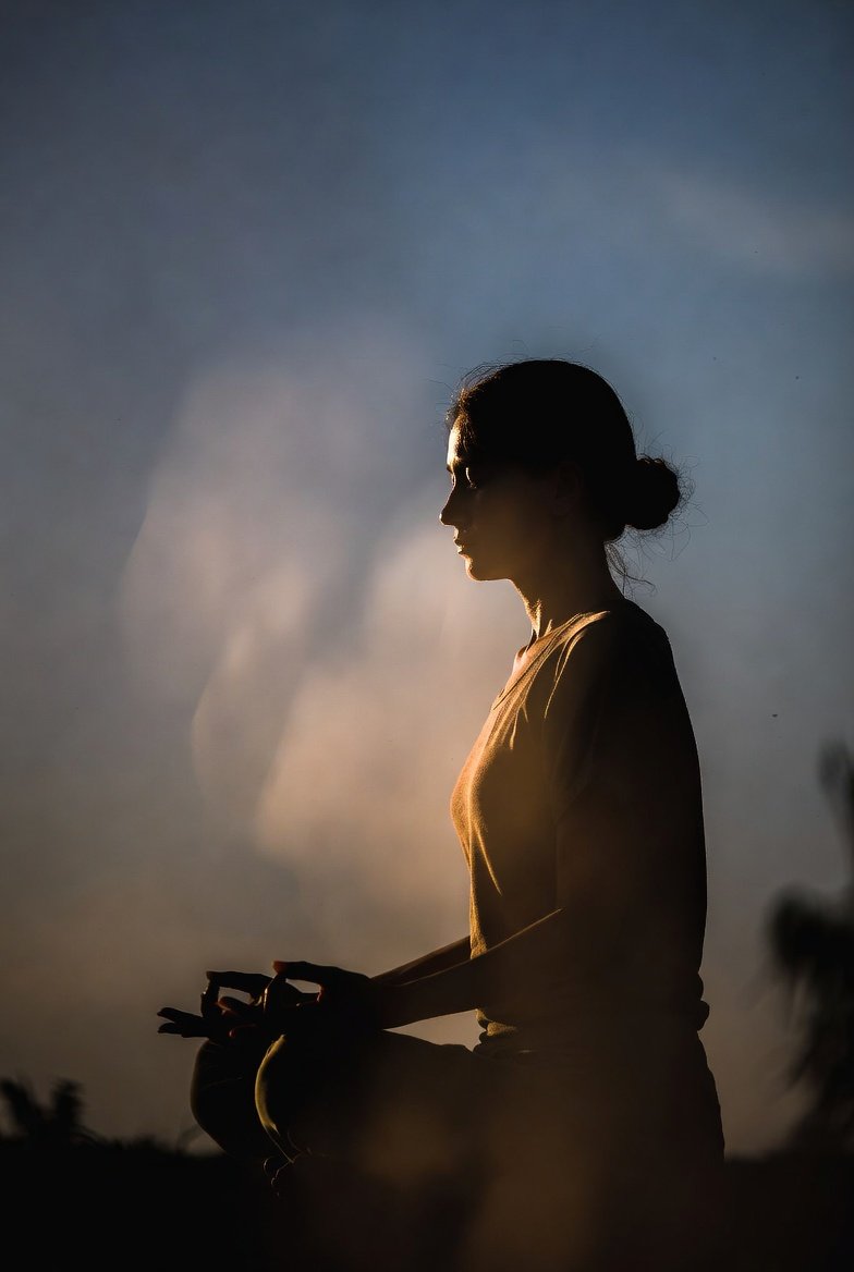 Mulher praticando meditação mindfulness ao amanhecer - técnicas do aqui e agora